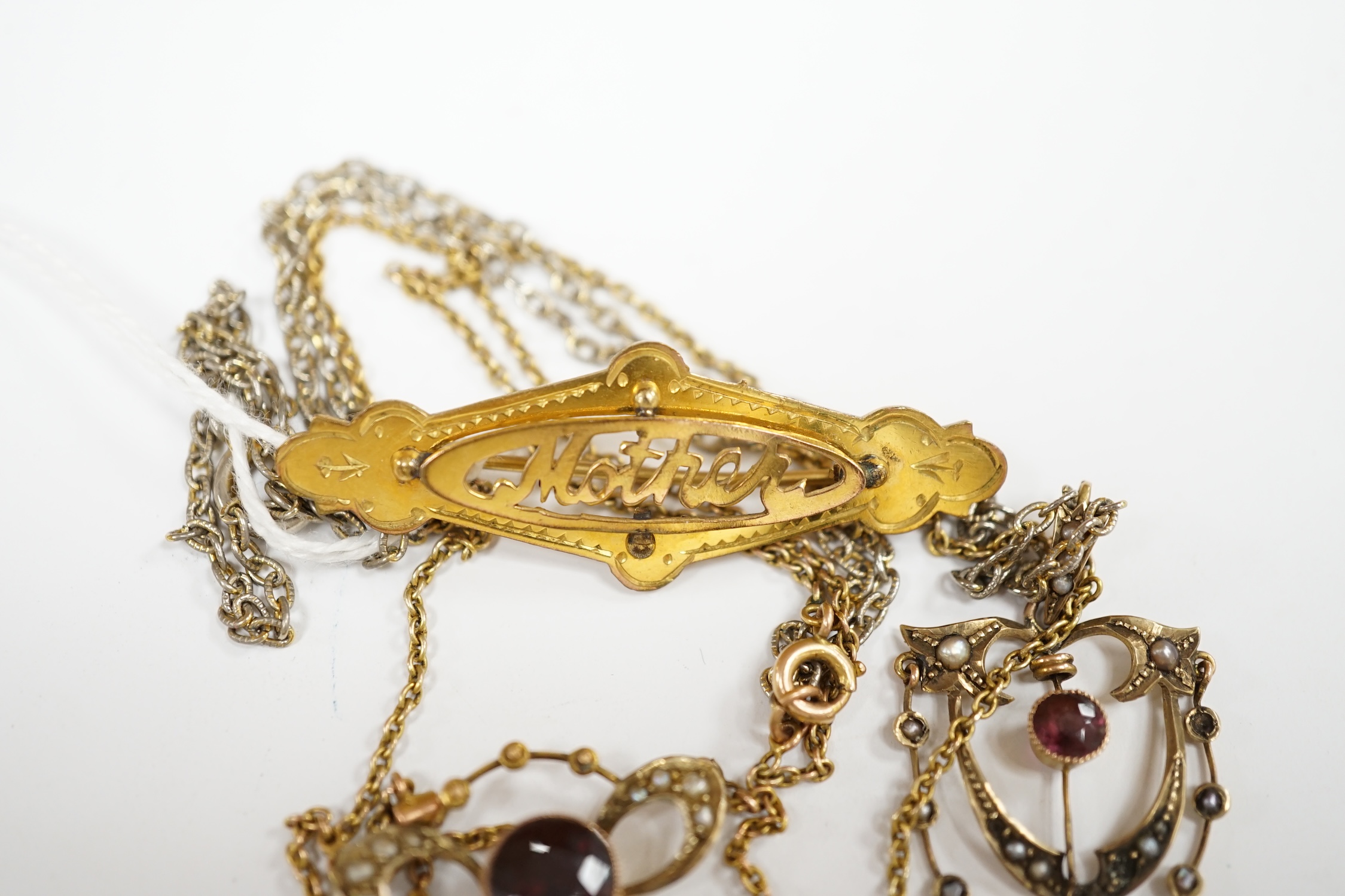 An early 20th century 9ct, garnet and seed pearl set pendant necklace, 43cm, one other similar 9ct and gem set pendant, on a gilt metal chain and a yellow 'metal 'mother' brooch. Condition - fair